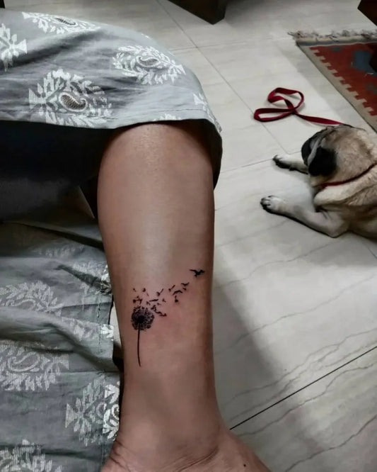 Small Fine Line Dandelion and Seeds Tattoo on Women Leg by @cosmic_ego_ink