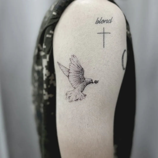 Small Fine Line Dove with Olive Branch Tattoo on Men Shoulder by @tattoogo_studio