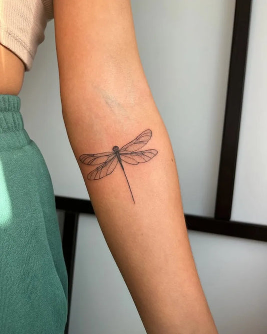 Small Fine Line Dragonfly on Women Arm Tattoo by @nickymarijnetattoo