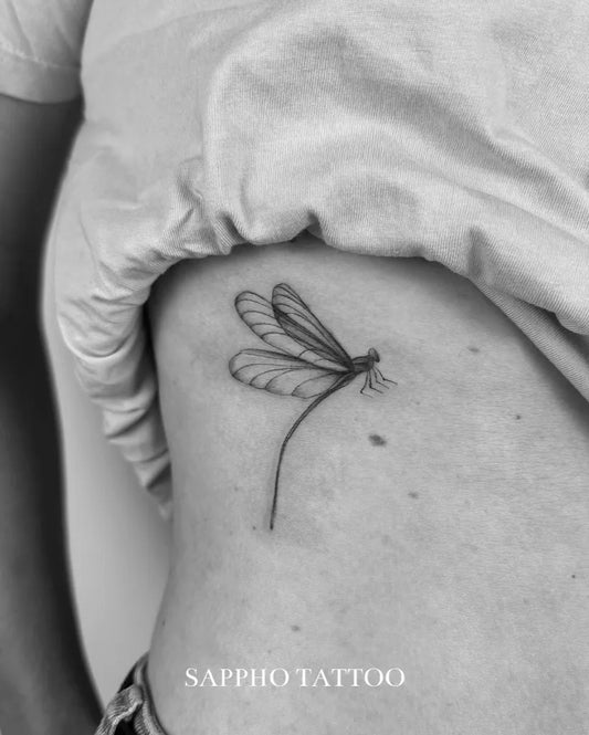 Small Fine Line Dragonfly on Women Rib Tattoo by @sappho.tattoo