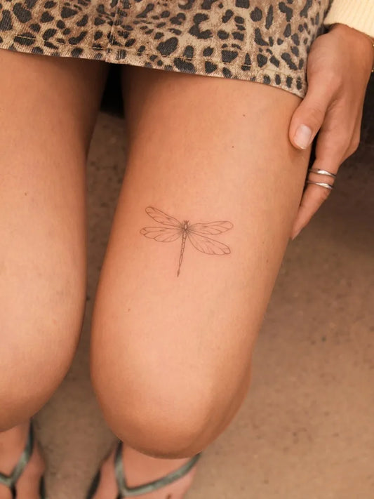 Small Fine Line Dragonfly on Women Thigh Tattoo by @julesdrytattoo