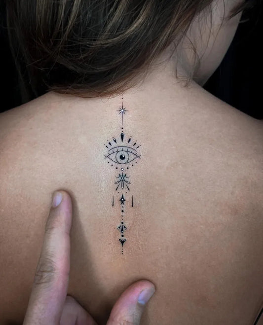 Small Fine Line Evil Eye Spine Design on Women Back Tattoo by @cachotattoo