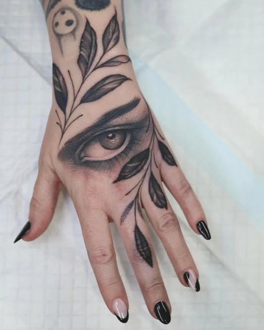 Small Fine Line Eye and Leaves on Women Hand Tattoo by @tattoo.faisal