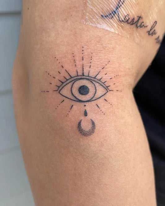Small Fine Line Eye with Tear and Crescent Moon on Women Thigh Tattoo by @inkbeautytherapy