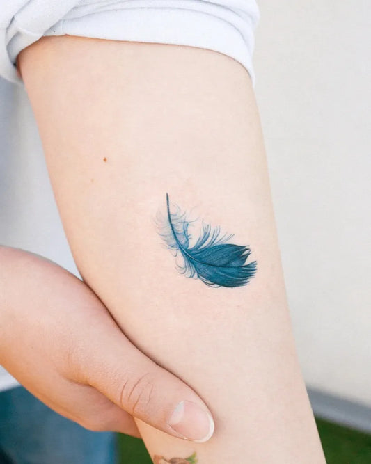 Small Fine Line Feather Tattoo on Women Arm by @hansantattoo
