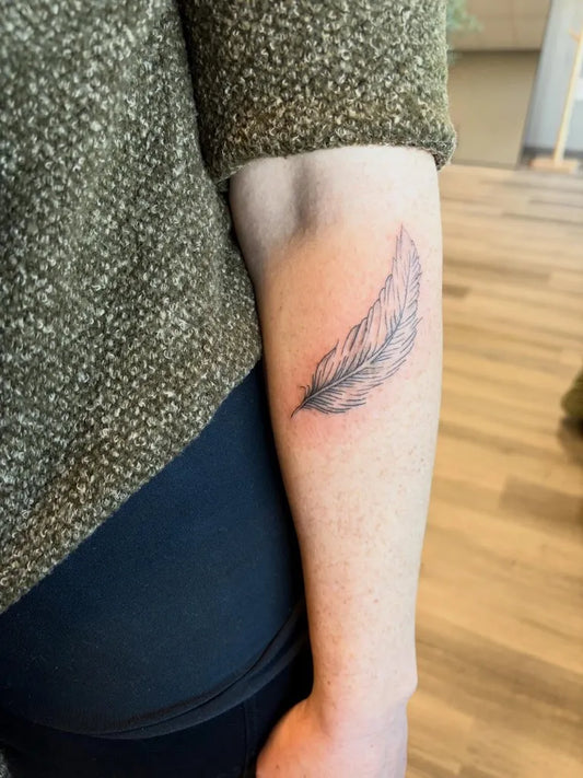 Small Fine Line Feather Tattoo on Women Arm by @inked.blooms.by.beth