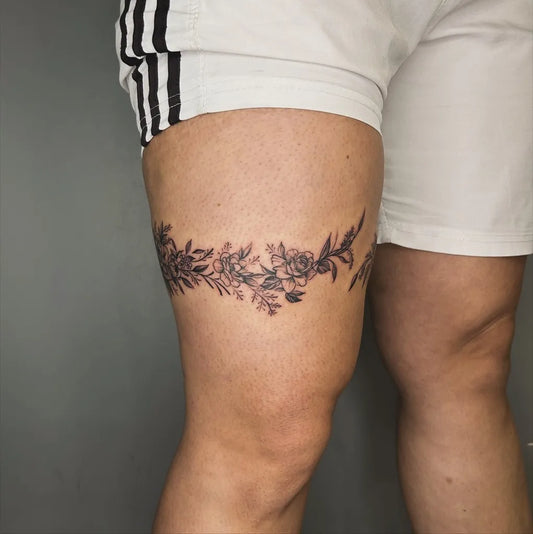 Small Fine Line Floral Garland on Women Thigh Tattoo by @ronnietattoos