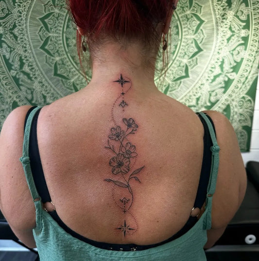 Small Fine Line Flowers and Stars on Women Spine Tattoo by @thetattoocabin