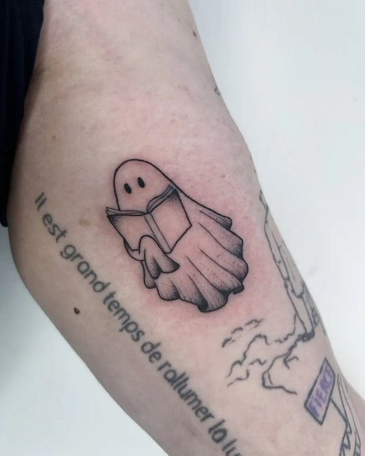 Small Fine Line Ghost Reading Book Tattoo on Women Arm by @poppyoliviatattoo