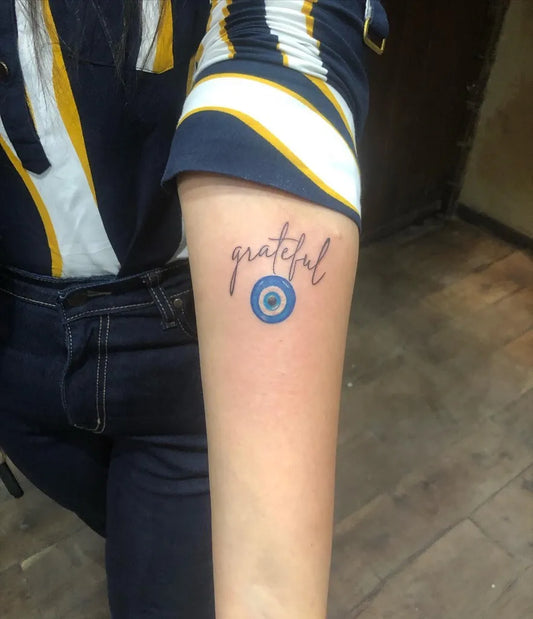 Small Fine Line Grateful and Evil Eye on Women Arm Tattoo by @nicktattoostudio