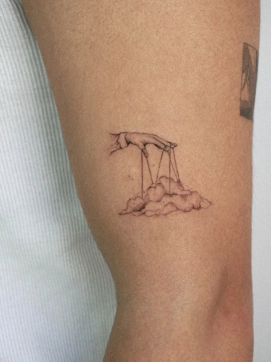 Small Fine Line Hand Over Cloud Tattoo on Women Thigh by @ki.te.kat