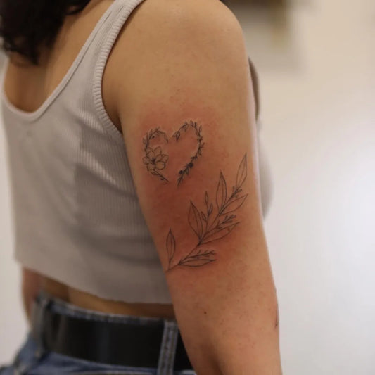 Small Fine Line Heart with Barbed Wire and Leaves Tattoo on Women Upper Arm by @breescarano