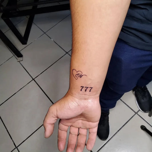 Small Fine Line Heart with Om and 777 Tattoo on Men Wrist by @jaguar_d_obsidiana