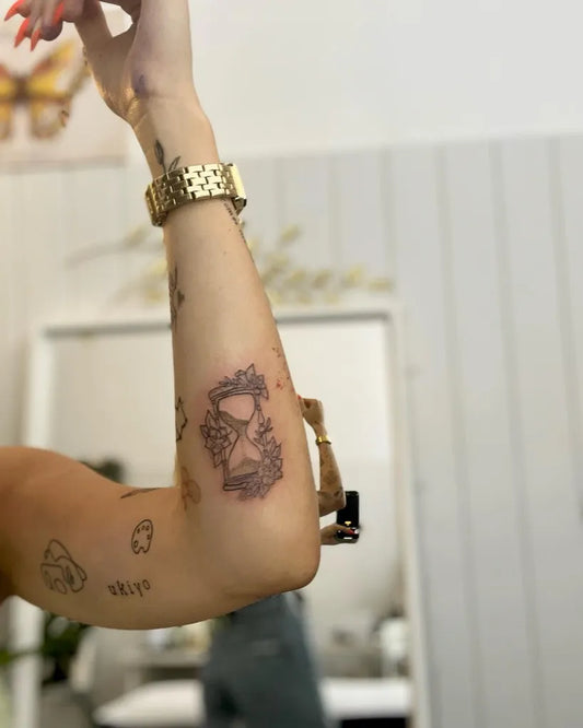 Small Fine Line Hourglass and Flowers Tattoo on Women Forearm by @mafaldadiego_