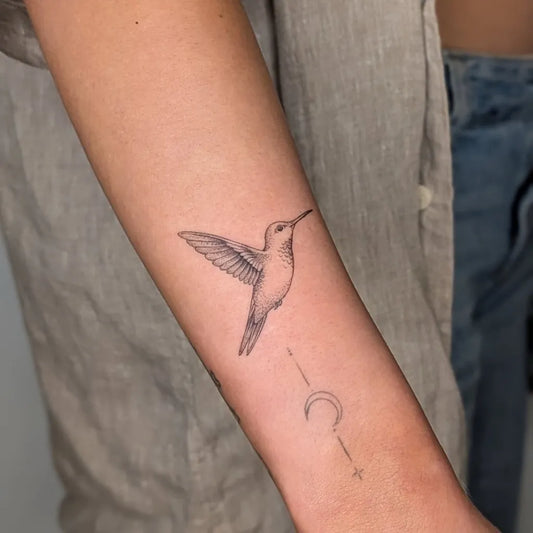 Small Fine Line Hummingbird Crescent Arrow on Women Arm Tattoo by @three_castles_tattoo