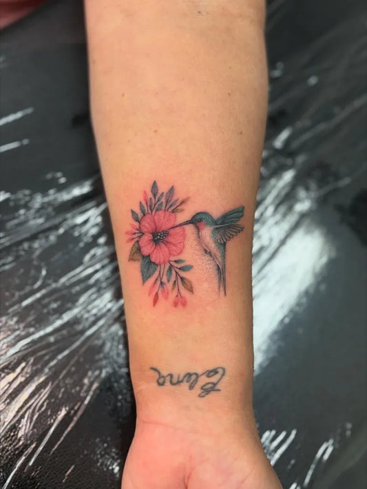 Small Fine Line Hummingbird and Hibiscus Flower on Women Wrist Tattoo by @ailurophile_tattoos