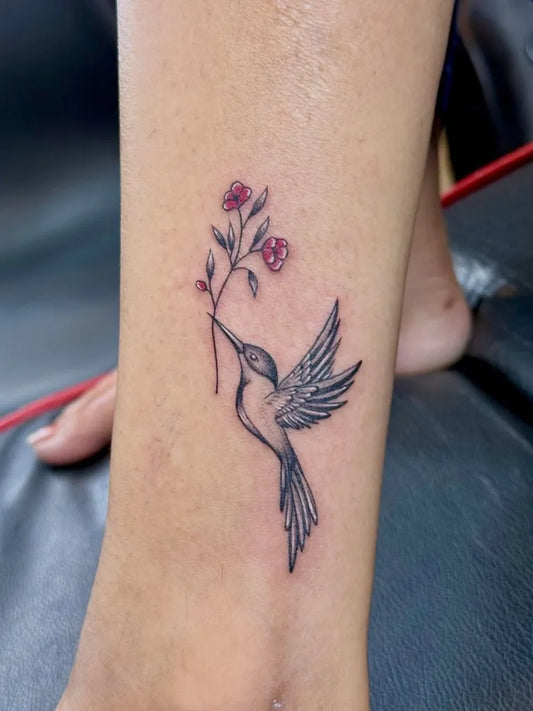 Small Fine Line Hummingbird with Flowers on Women Ankle Tattoo by @grand_paa_tattoo
