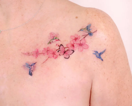 Small Fine Line Hummingbirds Cherry Blossoms Butterflies Tattoo on Women Collarbone by @peria_tattoo