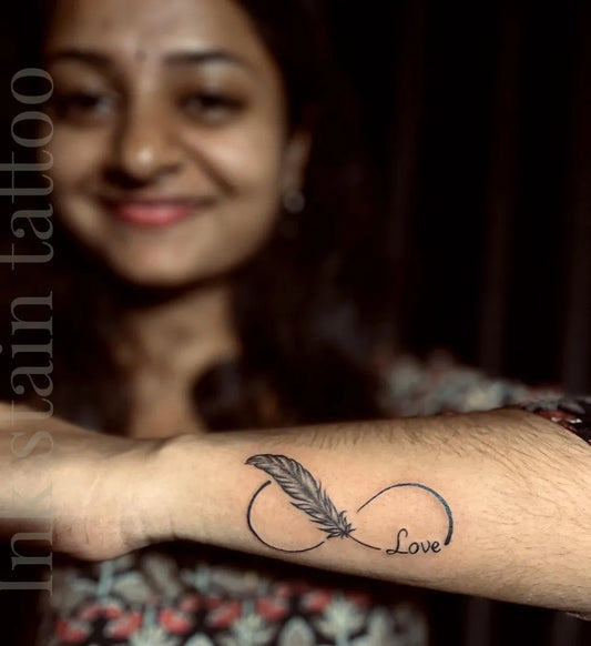 Small Fine Line Infinity Feather Tattoo on Women Wrist by @ink_stain__tattoostudio