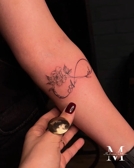 Small Fine Line Infinity and Flower Tattoo on Women Forearm by @mahsatattoo.ink