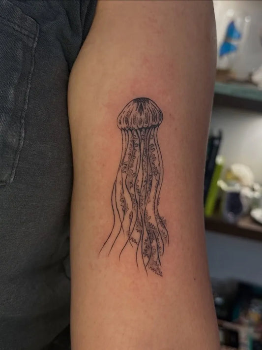 Small Fine Line Jellyfish Tattoo on Women Upper Arm by @artfully.adria