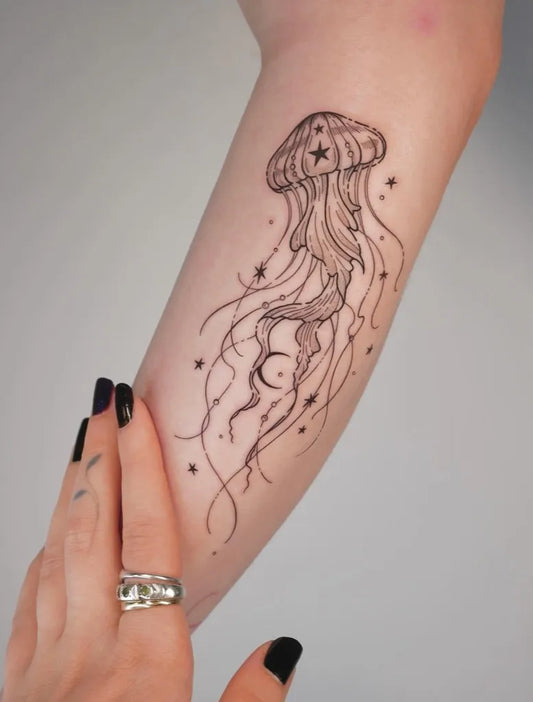 Small Fine Line Jellyfish with Stars Tattoo on Women Arm by @nameless.tattooist