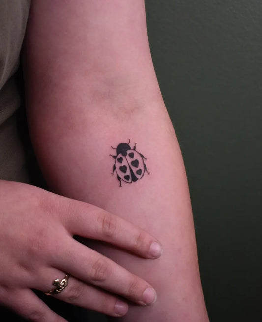 Small Fine Line Ladybug Tattoo on Women Arm by @ghostorchid.ink