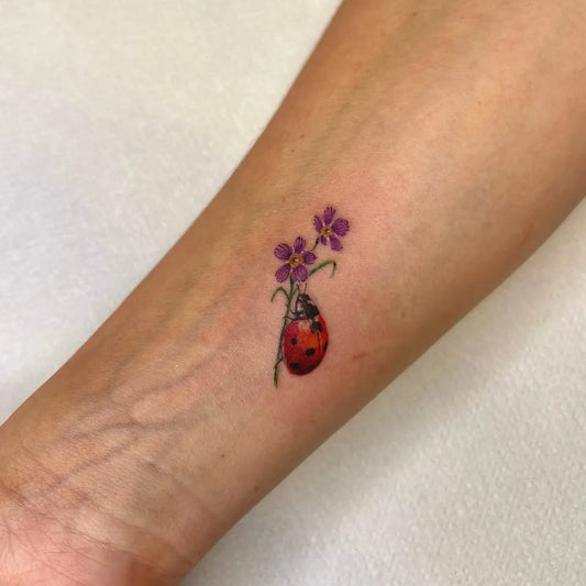 Small Fine Line Ladybug and Flowers Tattoo on Women Arm by @jesstattooing