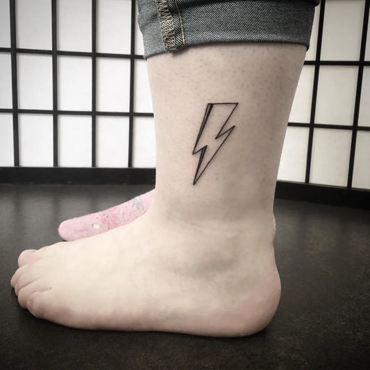 Small Fine Line Lightning Bolt Tattoo on Women Ankle by @mizt.tattoo