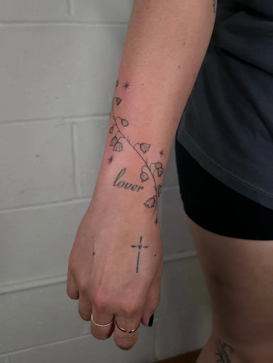 Small Fine Line Lily of the Valley and Cross on Women Wrist Tattoo by @baby.kait