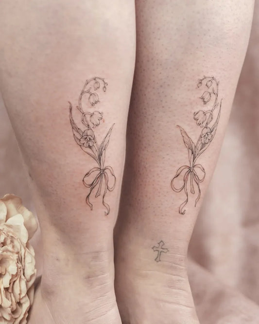 Small Fine Line Lily of the Valley with Bow on Women Leg Tattoo by @celinelilytattoo