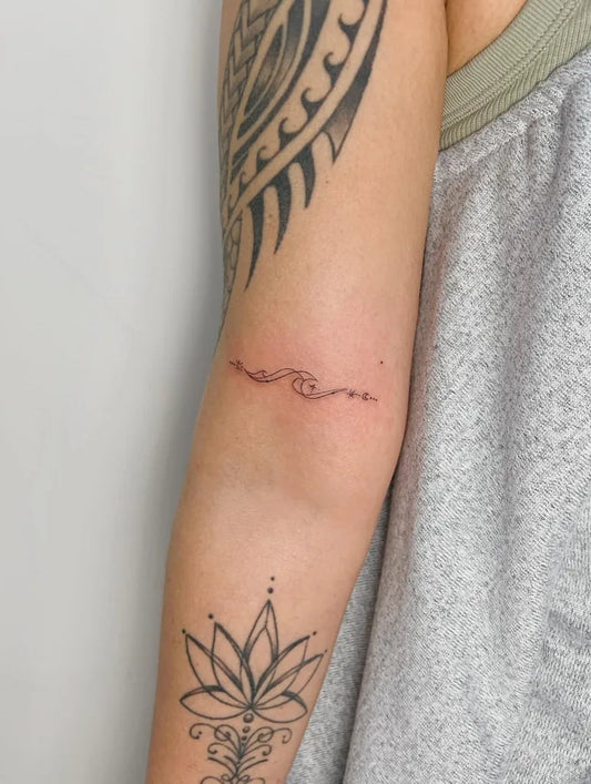 Small Fine Line Lotus Wave Tattoo on Women Arm by @inkedbyamanie