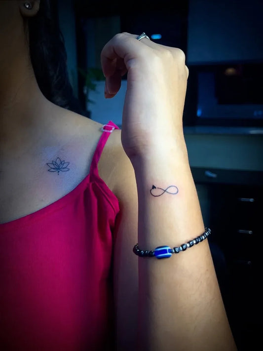 Small Fine Line Lotus and Infinity Tattoo on Women Shoulder by @gtr.tattoos