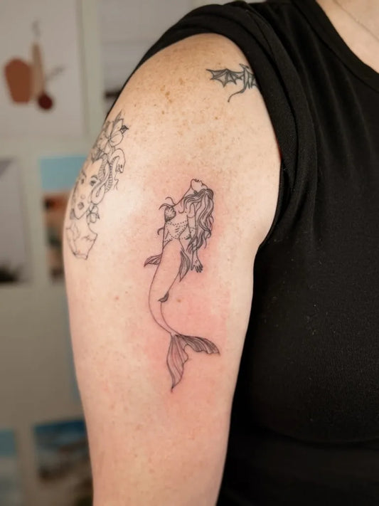 Small Fine Line Mermaid Tattoo on Women Upper Arm by @rbktatts