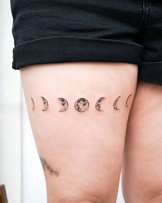 Small Fine Line Moon Phases Tattoo on Women Thigh by @casey.tat