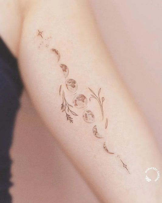 Small Fine Line Moon Phases and Flowers Tattoo on Women Arm by @noisette.tattoo