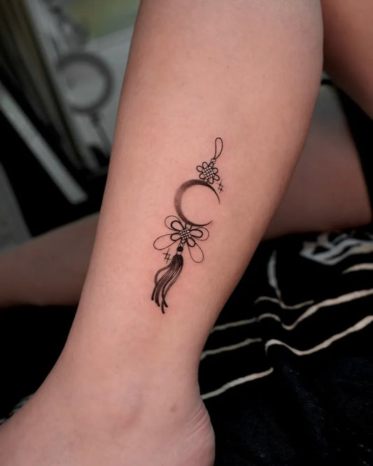 Small Fine Line Moon Tassel Tattoo on Women Leg by @hwana.tt