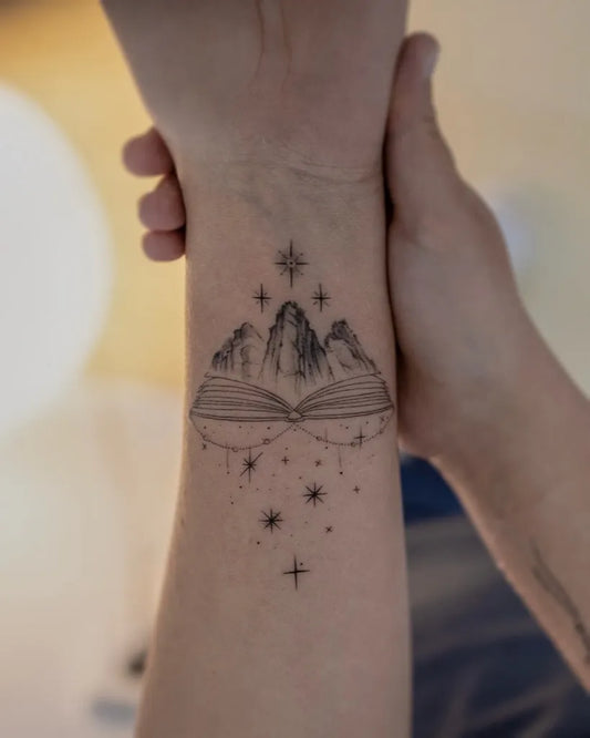 Small Fine Line Mountain Book Tattoo on Women Wrist by @logoom_tattooist