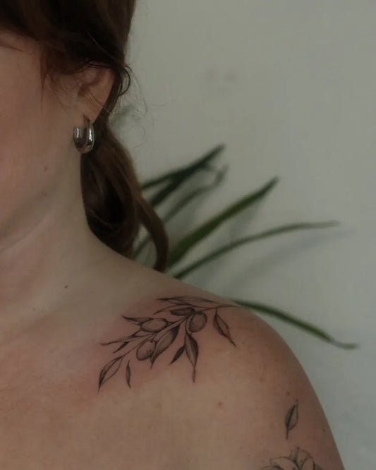 Small Fine Line Olive Branch Tattoo on Women Shoulder by @lovemore.tattoo