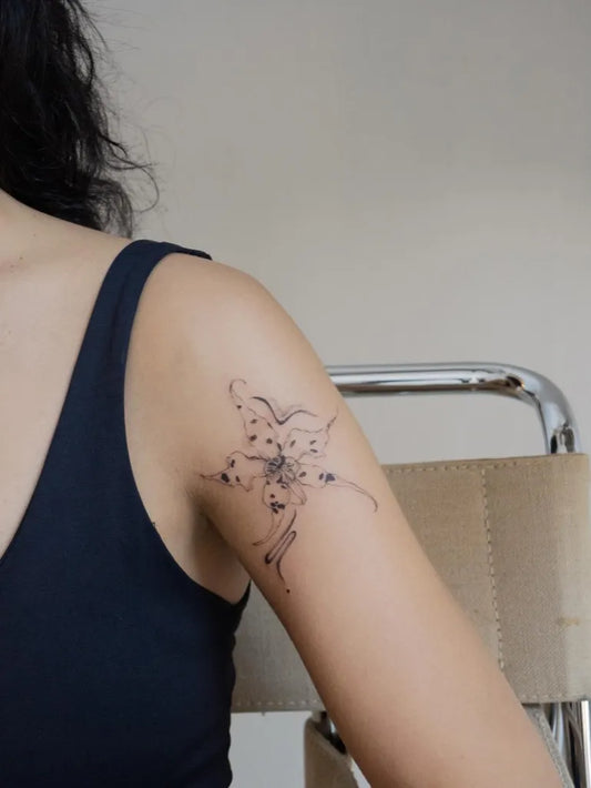 Small Fine Line Orchid Tattoo on Women Shoulder by @barbaracolla.tattoo