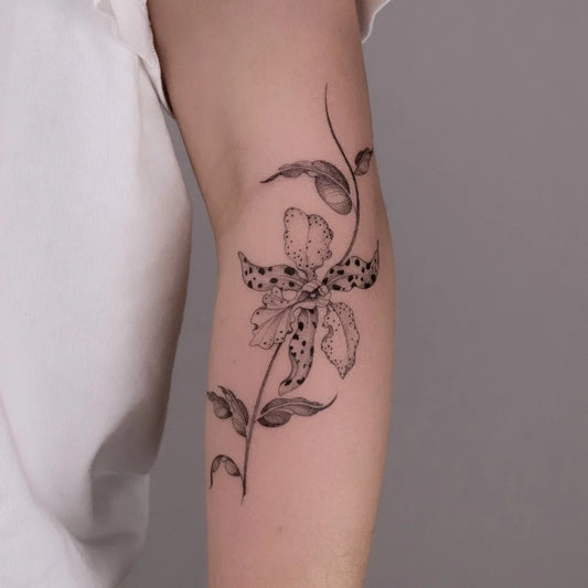 Small Fine Line Orchid and Vines Tattoo on Women Arm by @justynatattoos