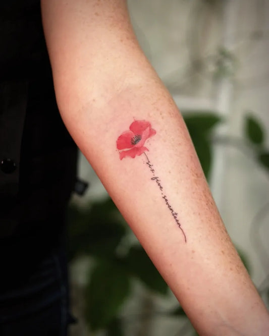 Small Fine Line Poppy with Text Tattoo on Women Arm by @vvstattoo