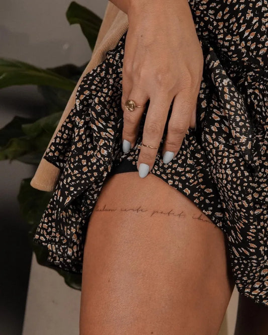 Small Fine Line Quote Tattoo on Women Thigh by @maff.leal