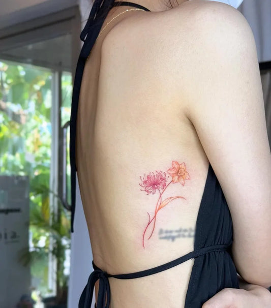 Small Fine Line Red and Orange Spider Lily Tattoo on Women Rib by @d.mension_tattoo