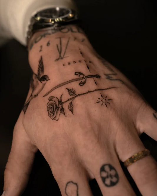 Small Fine Line Rose Bird Cross on Men Hand Tattoo by @dmenchitattoo