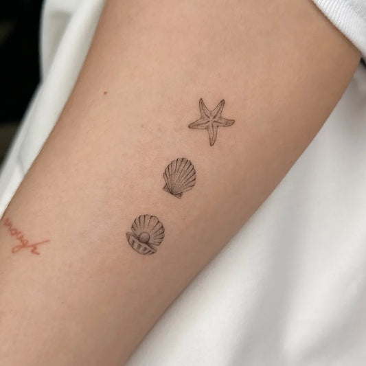 Small Fine Line Seashell Starfish on Women Arm Tattoo by @anna.inkd