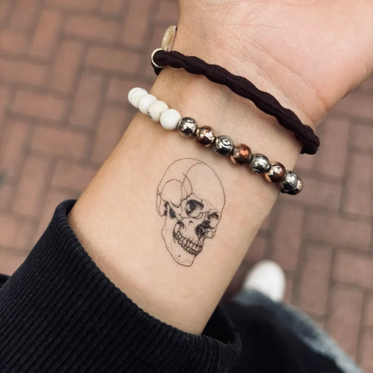 simple fine line skull temporary tattoo on women wrist