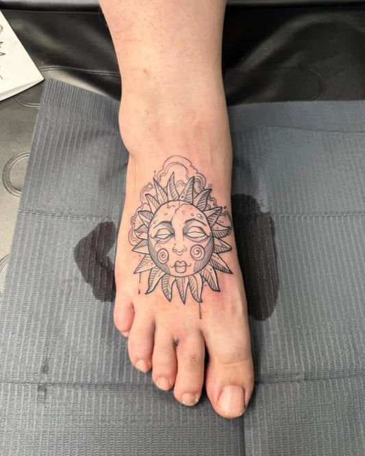 Small Fine Line Sun with Face on Women Foot Tattoo by @missionstreettattoo