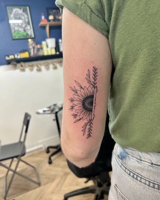 Small Fine Line Sunflower and Foliage on Women Arm Tattoo by @eightysixtattoostudio