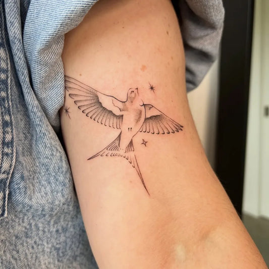 Small Fine Line Swallow with Stars Tattoo on Women Arm by @goodthanks.tattoo